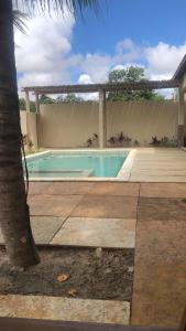a swimming pool in a yard with a tree at Pousada casa sonho do mar in Fortim