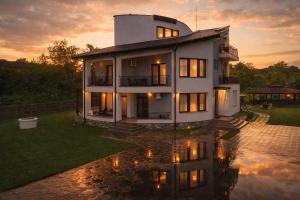a large white house with its reflection in the water at Pensiunea Casa Hortopan in Târgu Jiu