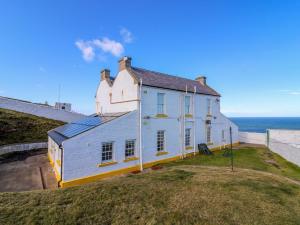 a white house on a hill next to the ocean at Lightkeepers Fold in Eyemouth