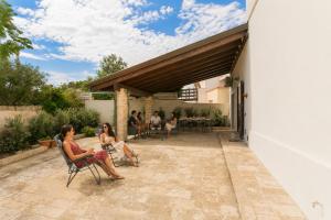 two women sitting in chairs on the patio of a house at Villa Stone and Sea Escape by Apulia Accommodation in Cozze