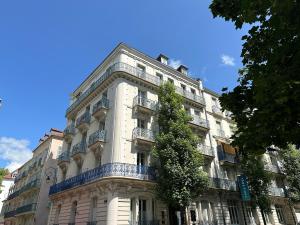a white building with a tree on the side of it at Appartement Standing proche des Thermes in Vichy