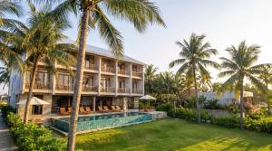 a resort with a swimming pool and palm trees at Rucha Beachfront Retreat in Ấp An Lộc A