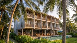 a building with a swimming pool and palm trees at Rucha Beachfront Retreat in Ấp An Lộc A