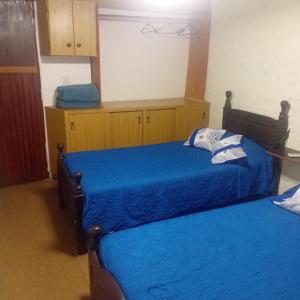 a bedroom with two beds with blue sheets at Punto Descanso in Corrientes