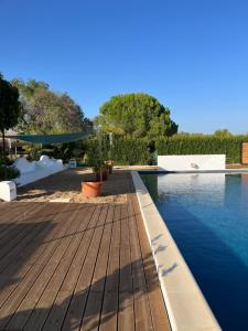 a swimming pool with a wooden deck and water at Monte da Palmeira in Vila Nova da Baronia