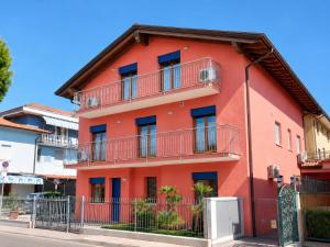 a red building with balconies on a street at Residence Guardamar - Agenzia Cocal in Caorle