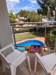 a balcony with a table and chairs and a swimming pool at Cala Llobeta in Calafat