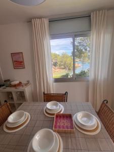 a dining room table with white plates and a window at Cala Llobeta in Calafat