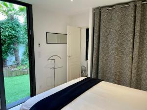a bedroom with a bed and a large window at Suite indépendante avec jardin, 2 chambres communicantes, hyper centre Arcachon in Arcachon +4 photos