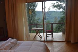 a bedroom with a bed and a balcony with a chair at Camphor Mountain View in Lushoto