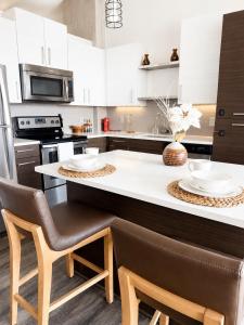 a kitchen with white cabinets and a counter with chairs at Ember Sky Penthouse in Atlanta