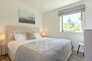 a white bedroom with a large bed and a window at 2 Bed in Colchester oc-82399 in East Bergholt