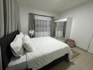 a bedroom with a white bed and a window at Vantage Suite in Lilongwe