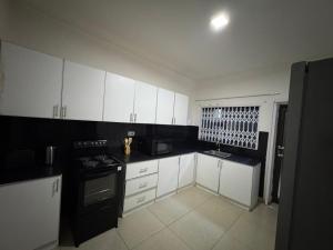 a kitchen with white cabinets and a black stove at Vantage Suite in Lilongwe
