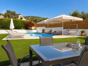a patio with a table and chairs and an umbrella at Villa Leonton with a private pool in Kissamos
