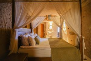 a bedroom with a canopy bed with white curtains at Helike Cave Suites in Uçhisar