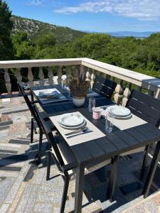 a wooden table with plates and glasses on a balcony at Apartment Barba in Bribir