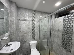 a bathroom with a shower and a toilet and a sink at Hostal Atlantis Middle World in Quito
