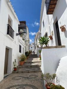 a narrow alley with white buildings and potted plants at Casa Verde - Ground floor apartment next to the beach in Torrox Costa