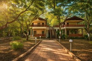 a brick walkway leading to a house with trees at The Wilds Villa Gir Jungle Stay with Swimming Pool in Sasan Gir +166 photos