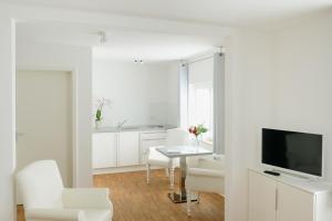 a white living room with a table and a tv at Bed & Breakfast Meerbusch in Meerbusch