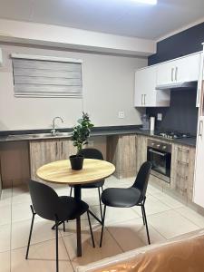 a kitchen with a wooden table and chairs and a table with a plant at Elisa's Haven in Matsulu