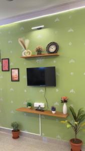 a green wall with a flat screen tv and a shelf at Trayi stay in Mysore +4 photos