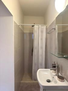 a white bathroom with a shower and a sink at Spiros apartment - Loggos, Paxos in Longós