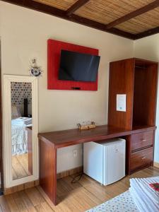 a room with a desk with a television on the wall at Chalés Casa de Vidro in Alter do Chao