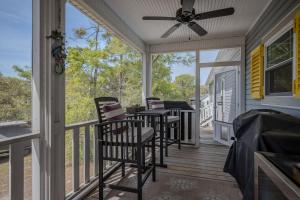 a screened porch with chairs and a ceiling fan at Chateau Relaxo by Oak Island Accommodations in Oak Island