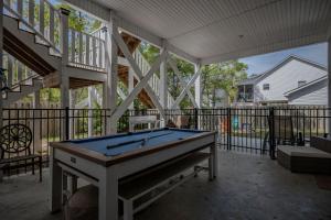 a pool table on a screened in porch with a staircase at Chateau Relaxo by Oak Island Accommodations in Oak Island
