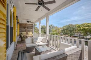 a porch with a couch and a ceiling fan at Chateau Relaxo by Oak Island Accommodations in Oak Island