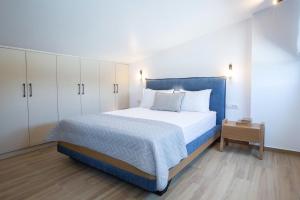 a bedroom with a bed with a blue headboard and white cabinets at Amalfi Twins Villa in Nydri +26 photos