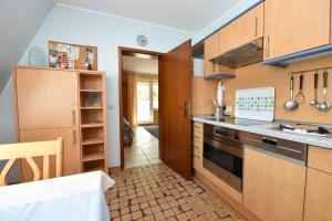 a kitchen with wooden cabinets and a stove top oven at Haus "Luv und Lee" Appartement LUV34 in Döse