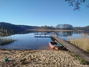 a boat parked next to a dock on a lake at Zakątek Wejsuny in Ruciane-Nida +12 photos