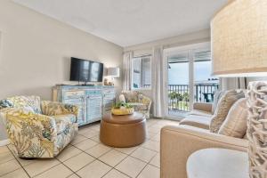 a living room with a television and a couch and chairs at Plantation East #2310 in Gulf Highlands