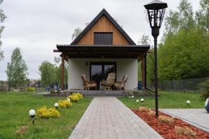 a small house with a porch and chairs in a yard at Domek letniskowy in Klusek Biały