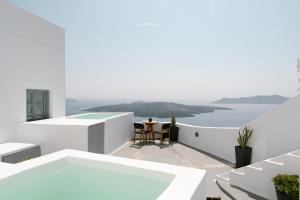 a white house with a swimming pool and a table at Anemos Fira Caldera View in Fira