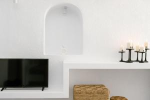 a living room with a tv and candles at Anemos Fira Caldera View in Fira