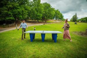 a man and woman standing next to a ping pong table at Camping 3 étoiles - Piscine - ccbfh0d in Saint-Amand-de-Coly