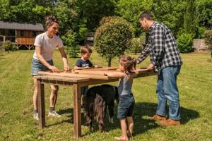 a family playing with a wooden table with a dog at Camping 3 étoiles - Piscine - ccbfh0d in Saint-Amand-de-Coly +21 photos