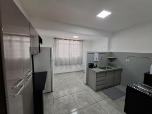 an empty kitchen with a refrigerator and a sink at Confortável & Bem Localizado! in Campo Grande