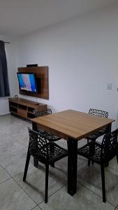 a wooden table with two chairs and a flat screen tv at Confortável & Bem Localizado! in Campo Grande
