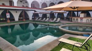 a pool with chairs and umbrellas next to a building at Hotel Hacienda Bugambilias La Paz in La Paz