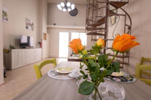 a dining room table with yellow flowers in a vase at Ciccio's House in Giardini Naxos