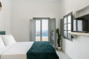 a white bedroom with a bed and a tv at Anemos Fira Caldera View in Fira