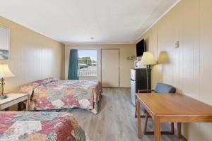 a hotel room with two beds and a desk and a table at Currys Motel by OYO Saginaw MI in Saginaw