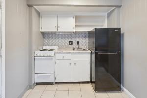 a kitchen with white cabinets and a black refrigerator at Currys Motel by OYO Saginaw MI in Saginaw