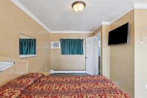 a hotel room with a bed and a flat screen tv at Currys Motel by OYO Saginaw MI in Saginaw