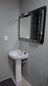 a bathroom with a white sink and a mirror at Confortável & Bem Localizado! in Campo Grande